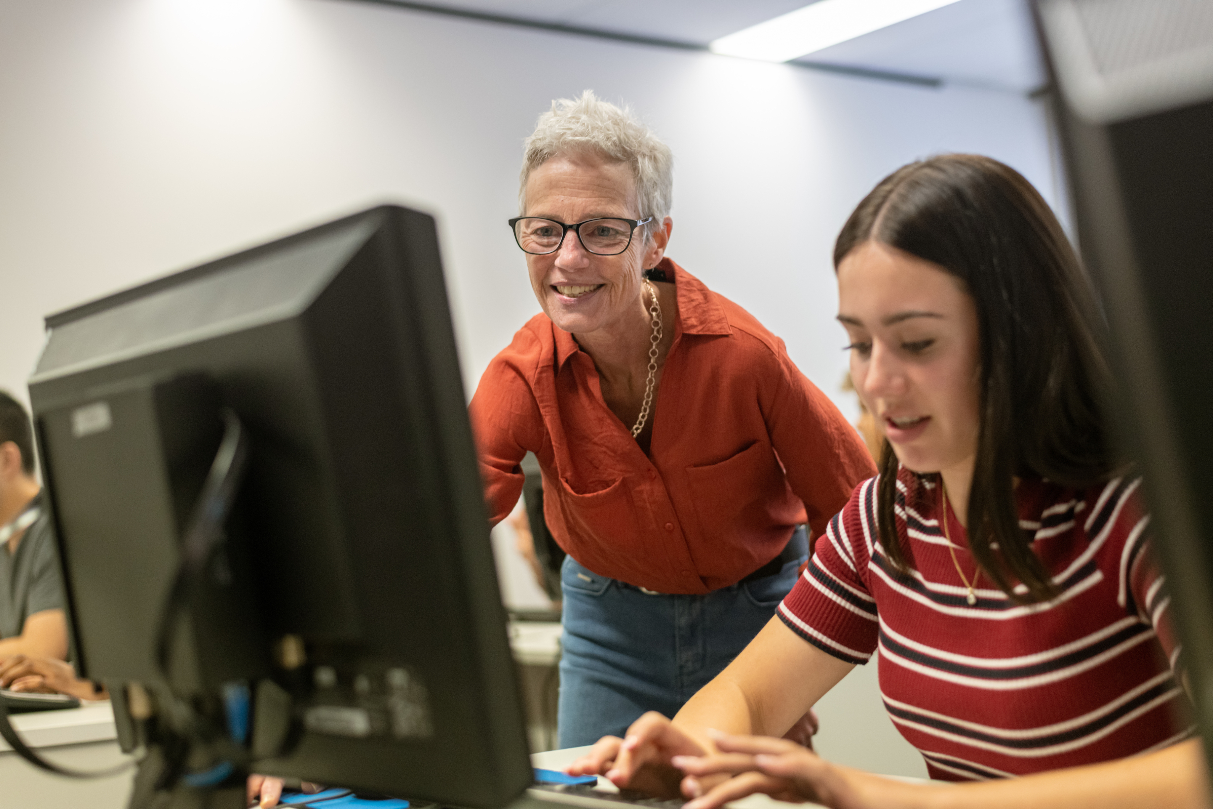 Female tutor assisting a female student at a computer. 