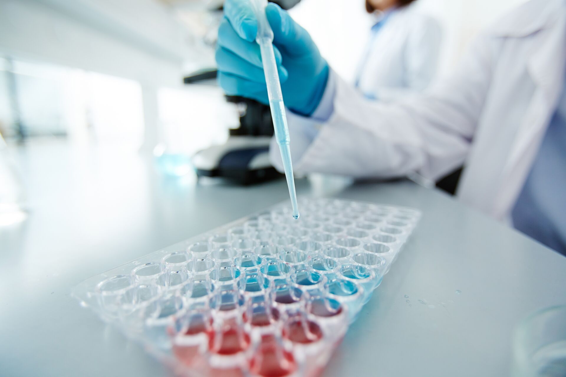 A close up of a scientist putting fluids into test tubes. 