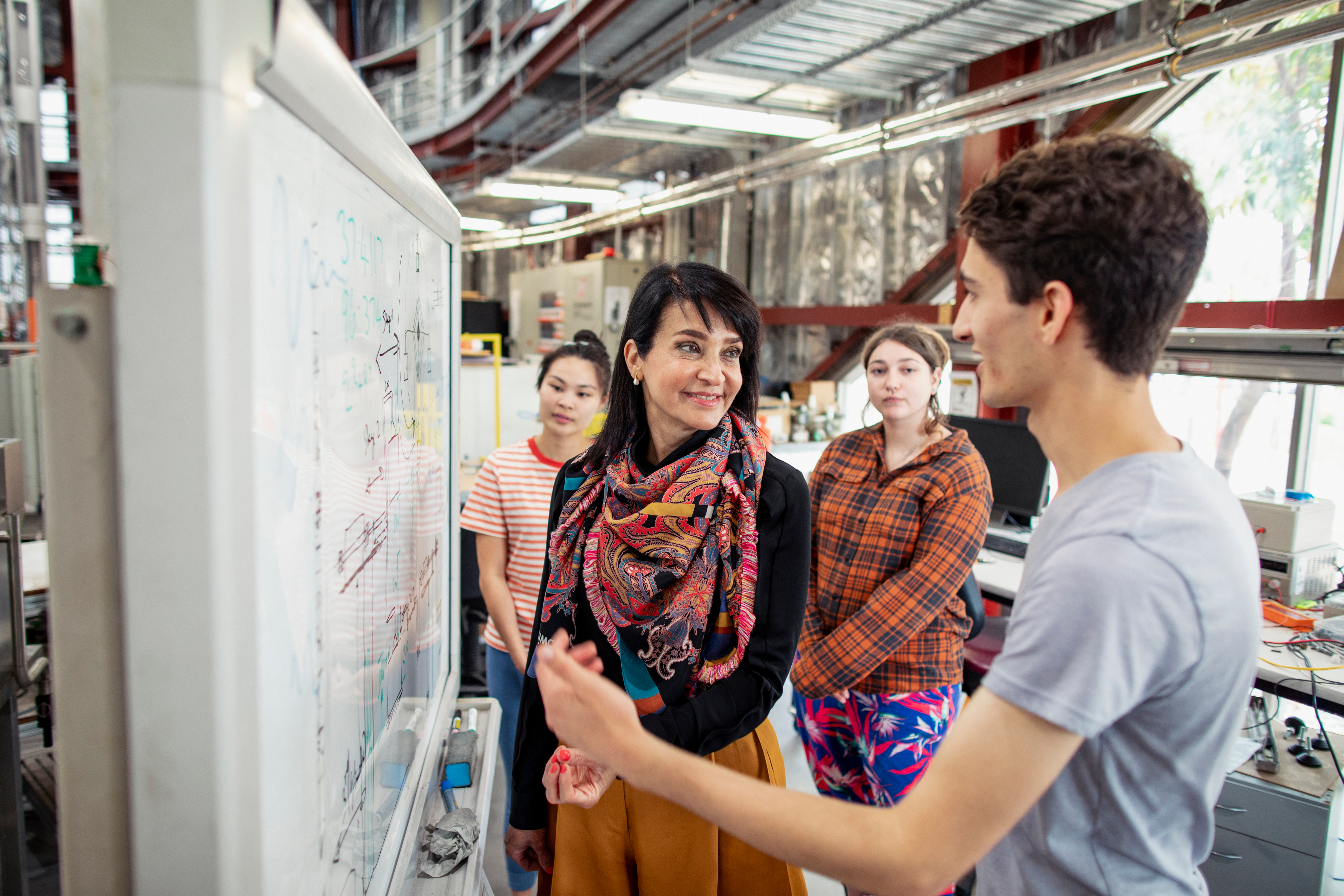 Group of students standing around a whiteboard. 