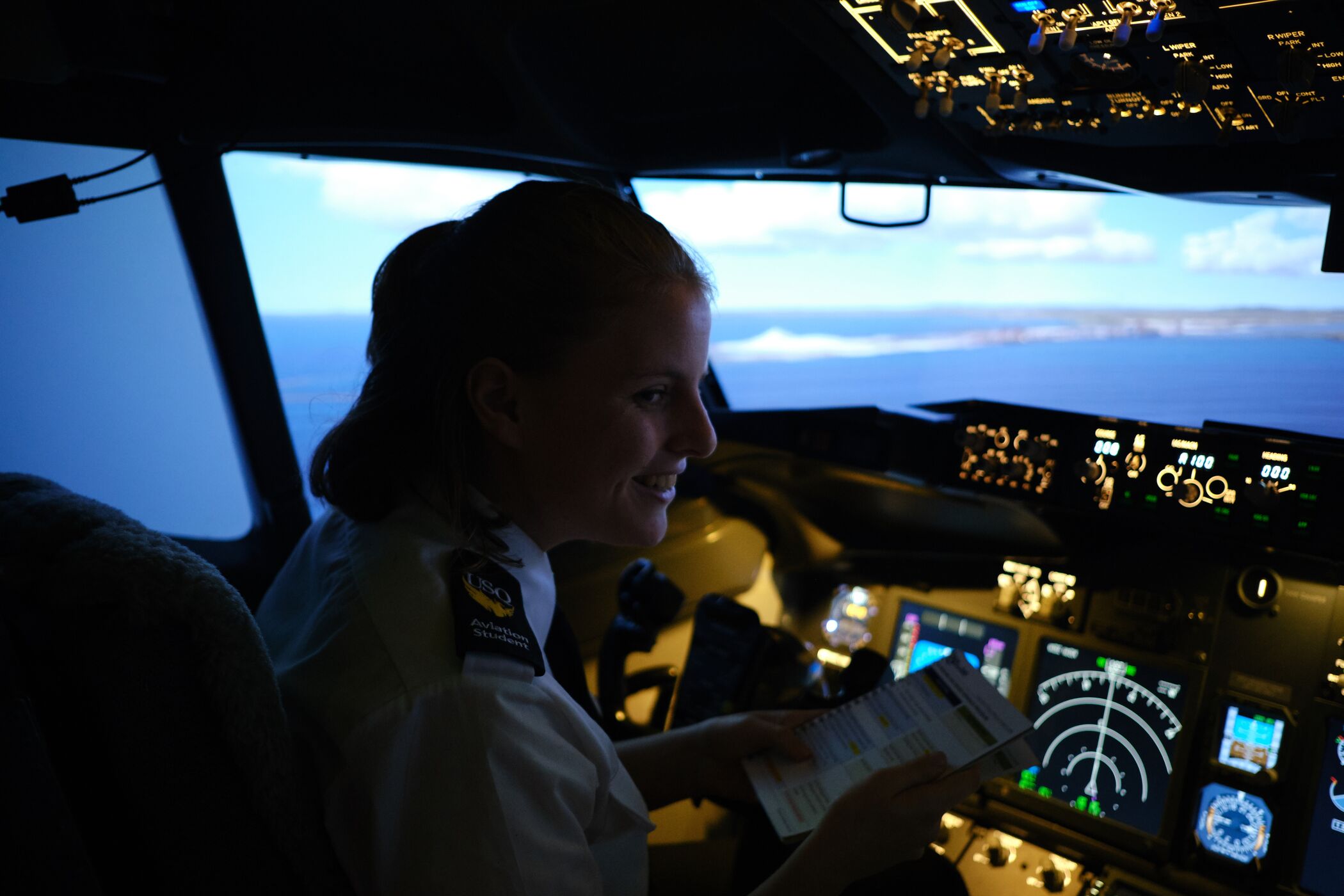 Female aviation student at UniSQ in a flight simulator. 