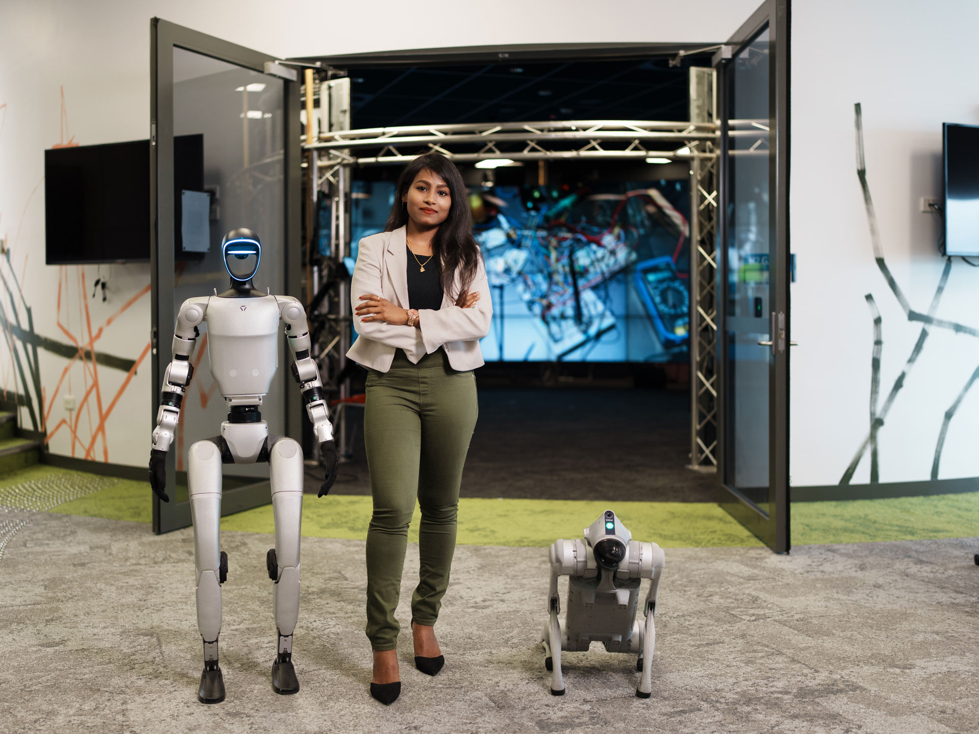 Female student standing with robots. 