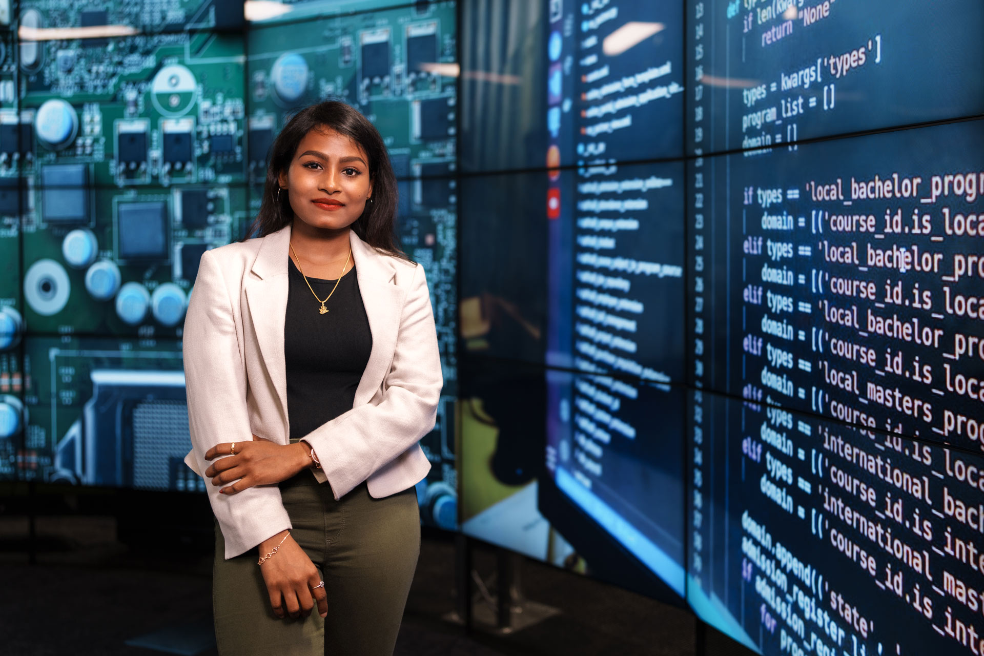 Female student standing next to a wall of digital code. 